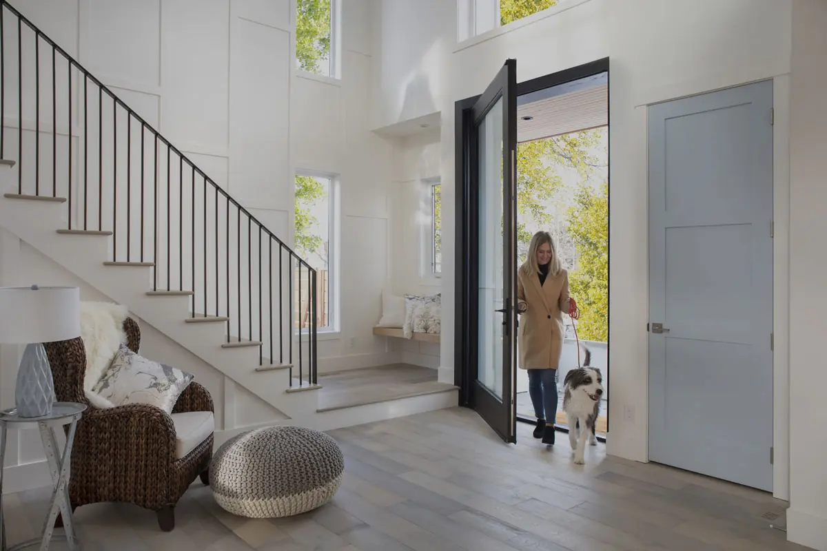 Woman walking into a luxury home with a dog